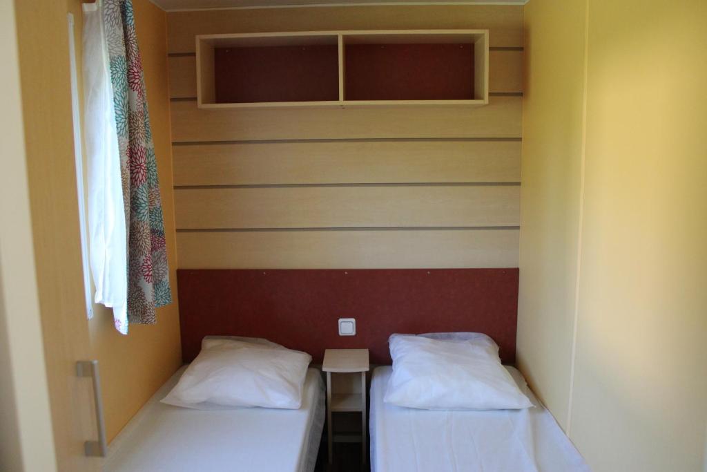 deux lits dans une petite pièce avec une fenêtre dans l'établissement Camping Familial paisible avec piscine, mobil home , chalet, Studio & emplacement nue, à Casties-Labrande