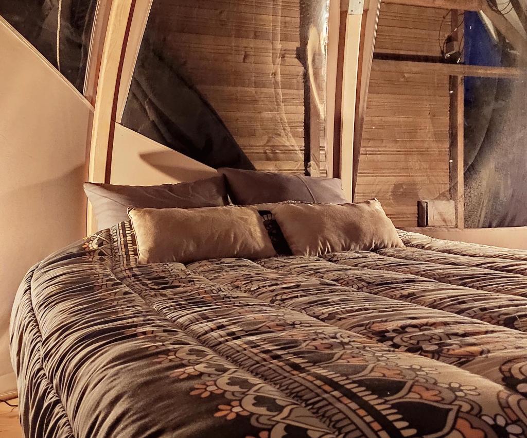 - un lit avec une tête de lit en bois et des oreillers dans l'établissement Le Wigwam du Fassac, à Saint-Julien-du-Puy