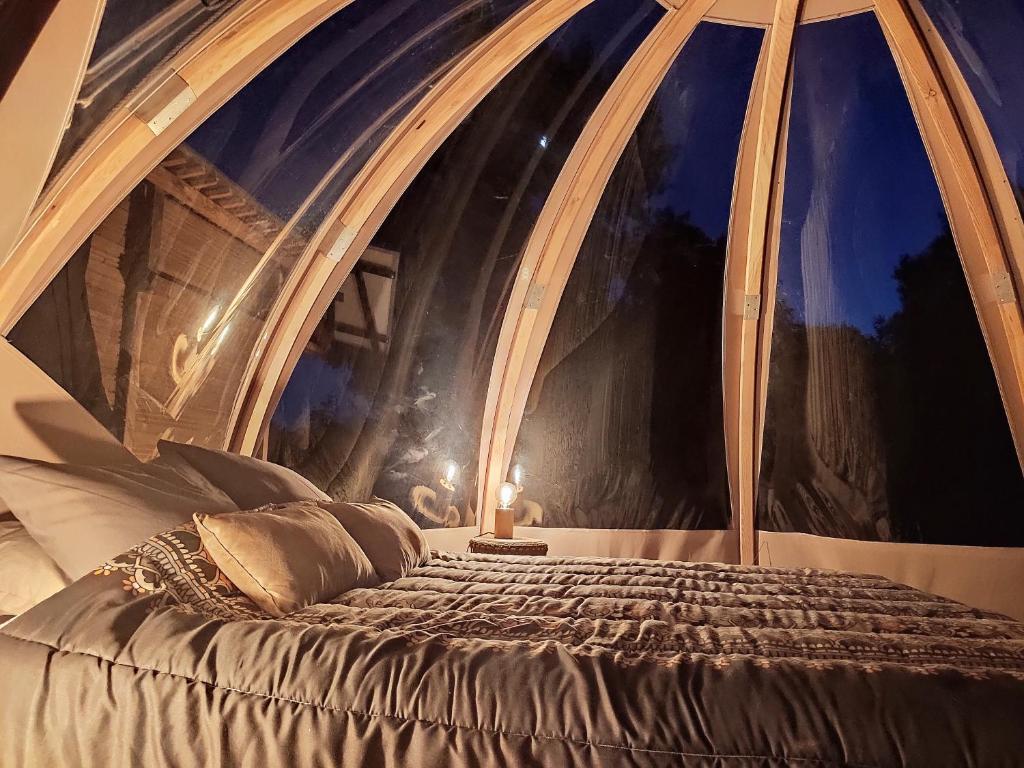 Ce lit se trouve dans un dortoir doté d'une fenêtre cintrée. dans l'établissement Le Wigwam du Fassac, à Saint-Julien-du-Puy