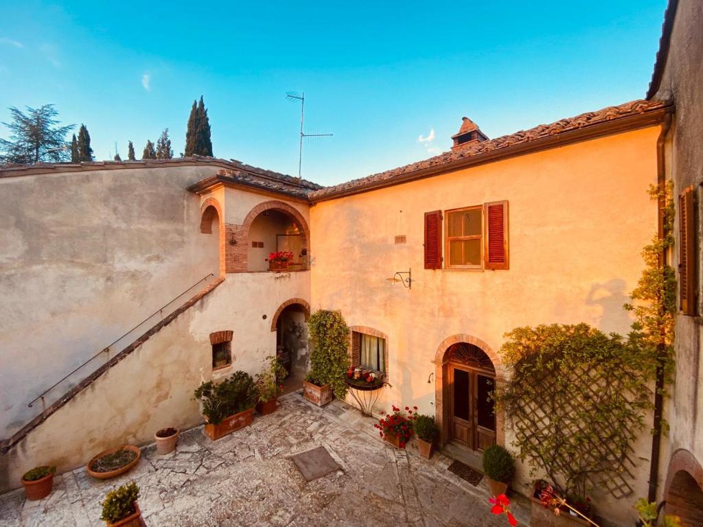 un vieux bâtiment avec des plantes en pot dans une cour dans l'établissement Casale Le Borghe - Montalcino,Toscana, à San Giovanni dʼAsso