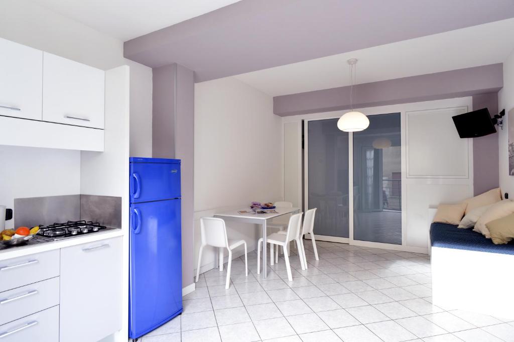 Il comprend une cuisine équipée d'un réfrigérateur bleu et d'une table avec des chaises. dans l'établissement Hotel & Residence Progresso, à Lido di Jesolo 11 autres photos