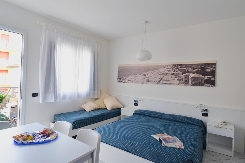 un salon avec deux lits et une table dans l'établissement Hotel & Residence Progresso, à Lido di Jesolo