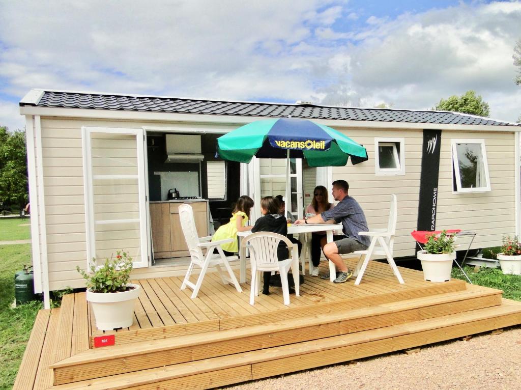 une famille assise à une table sur le pont d'une caravane dans l'établissement Camping Aux Rives du Soleil, à Pont-de-Vaux