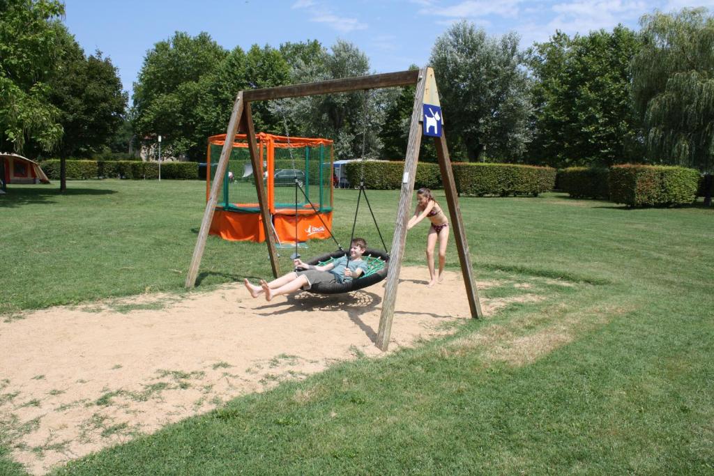2 personnes jouant sur une balançoire dans un parc dans l'établissement Camping Aux Rives du Soleil, à Pont-de-Vaux