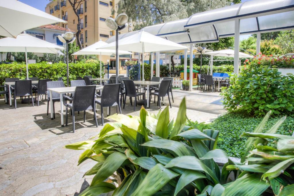 un patio extérieur avec tables, chaises et parasols dans l'établissement Hotel Taunus - Vista Mare, à Riccione