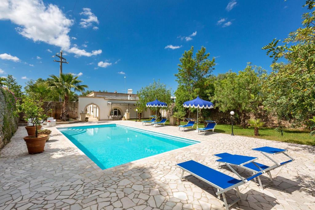 une piscine avec des chaises bleues et une maison dans l'établissement Villa Medici alla Macchia by BarbarHouse, à Oria