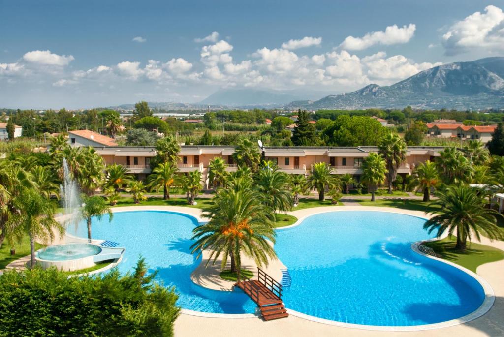 - une vue sur la piscine bordée de palmiers et d'une cascade dans l'établissement Minerva Resort Hotel, à Paestum