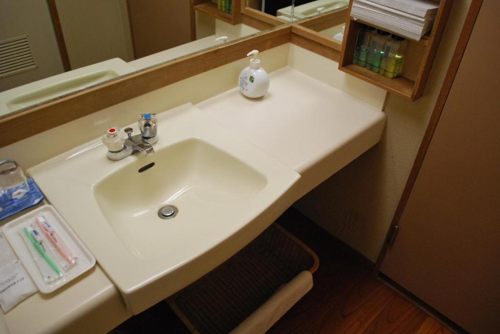 un lavabo blanc dans une salle de bain avec un miroir dans l'établissement Ryokan Tanigawa, à Minakami
