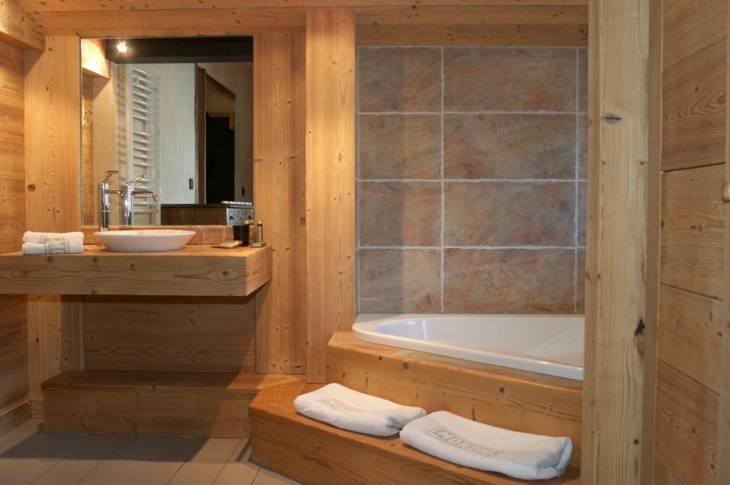 La salle de bains en bois est pourvue d'une baignoire et d'un lavabo. dans l'établissement Le Chalet Nativ, à Morzine