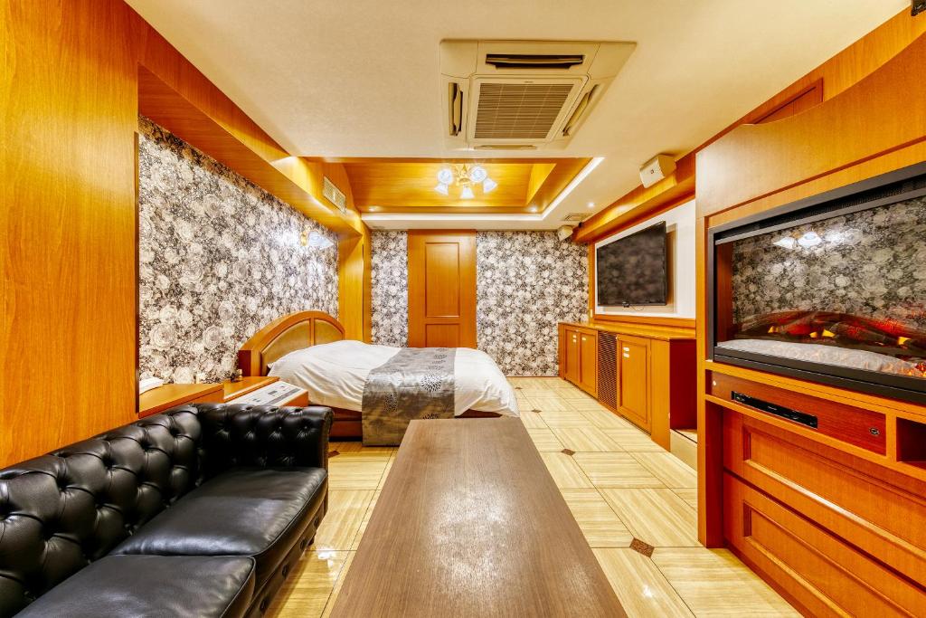 Cette chambre d'hôtel dispose d'un canapé et d'une télévision. dans l'établissement HOTEL LUNA Izumiotsu (Adult Only), à Shōki