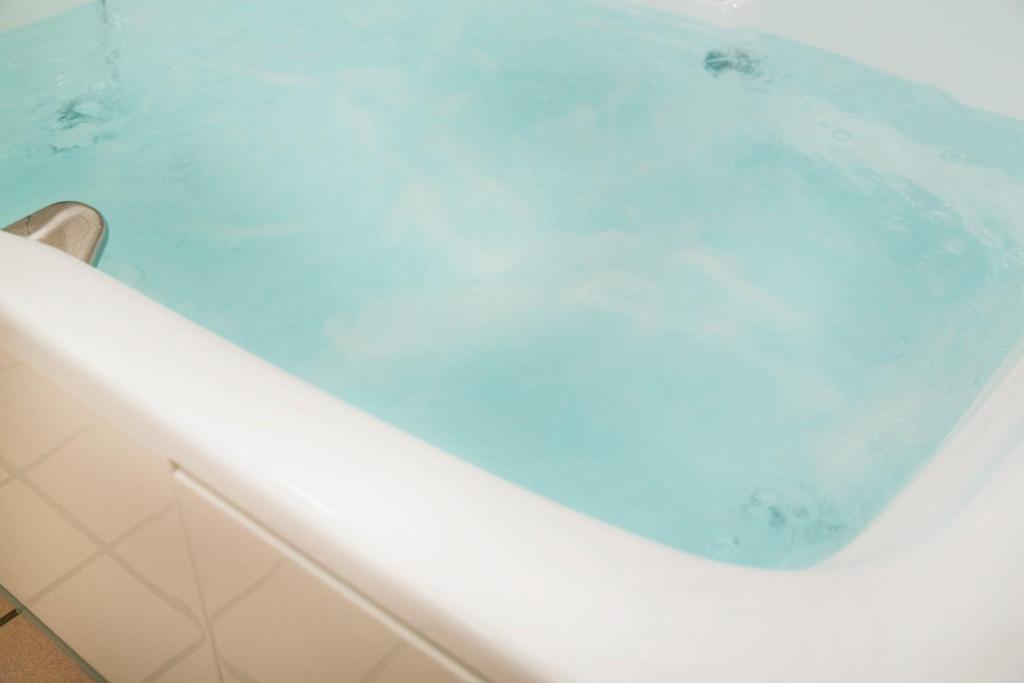 une baignoire remplie d'eau bleue dans une salle de bain dans l'établissement HOTEL LUNA Izumiotsu (Adult Only), à Shōki