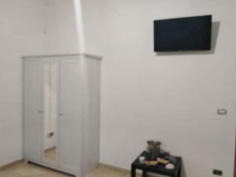 Cette chambre blanche dispose d'une télévision et d'une table avec un sidx de table. dans l'établissement Villa belvedere mini appartamento, à Pontecagnano