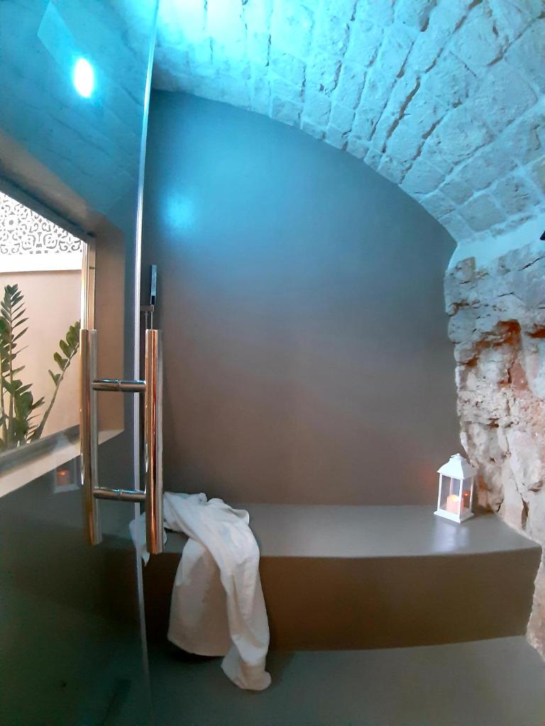 Cette chambre dispose d'un lit et d'un mur en pierre. dans l'établissement Borgo Aratico, à Monopoli