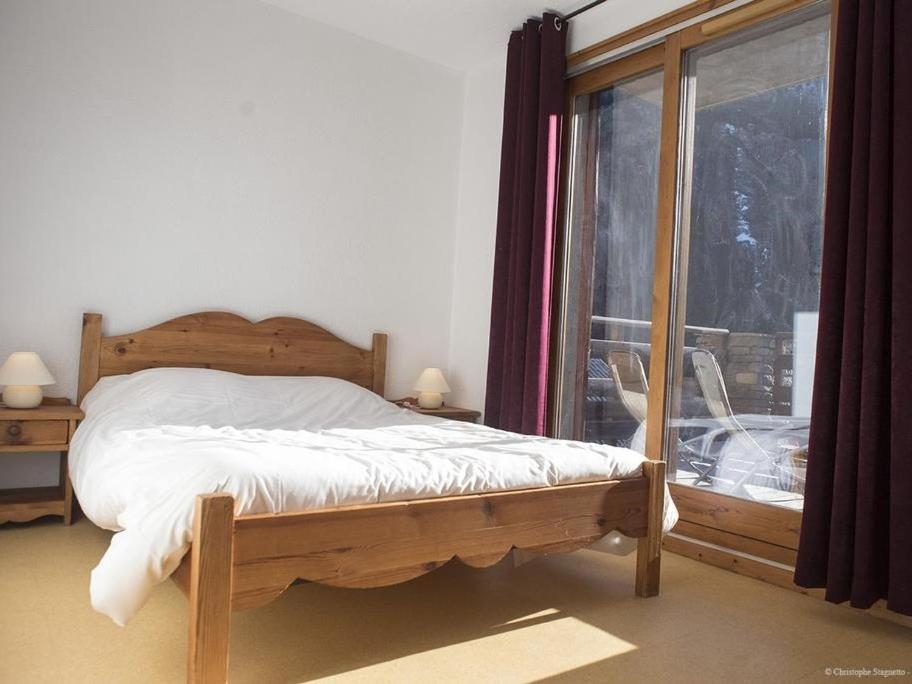 une chambre avec un lit en bois et une fenêtre dans l'établissement VAUJANYLOCATIONS - Chalet De Marie, à Vaujany