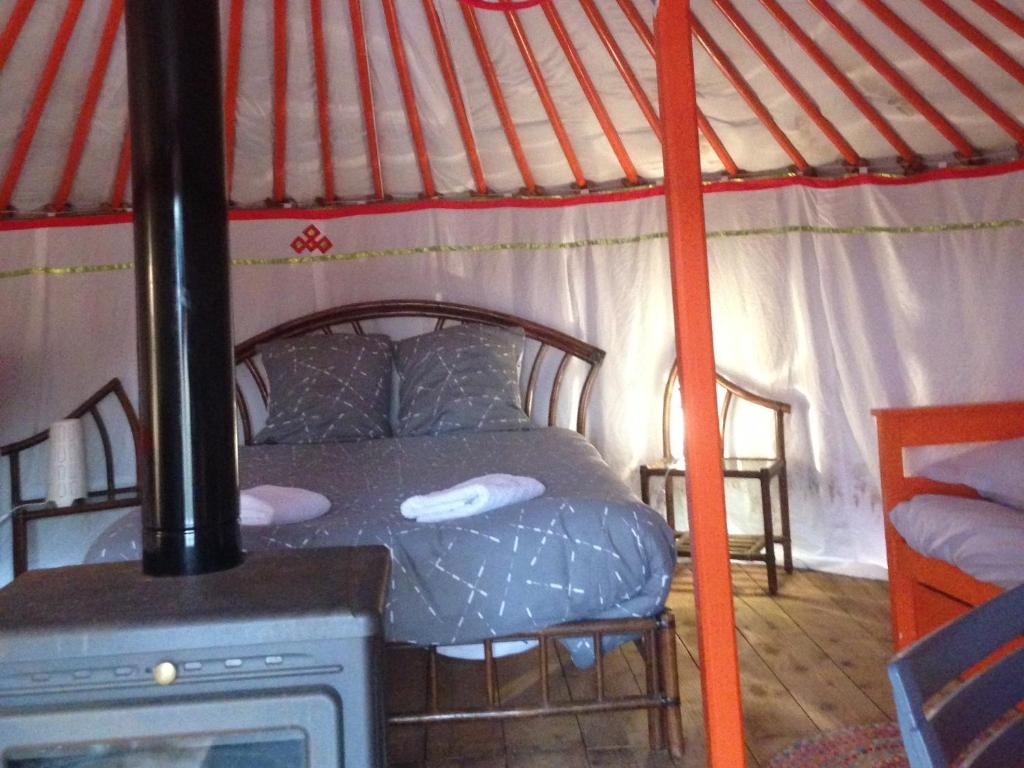 - une chambre avec un lit dans une yourte dotée d'une cuisinière dans l'établissement Yourte Mongole, à Saint-Léger-sur-Dheune