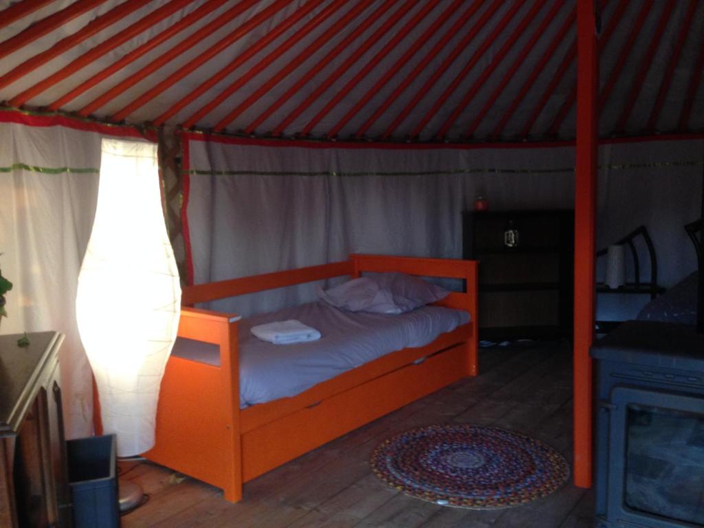 - une chambre avec un lit orange dans une tente dans l'établissement Yourte Mongole, à Saint-Léger-sur-Dheune
