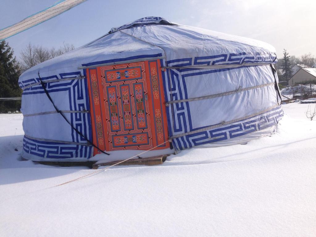 une yourte avec une porte rouge dans la neige dans l'établissement Yourte Mongole, à Saint-Léger-sur-Dheune 3 autres photos