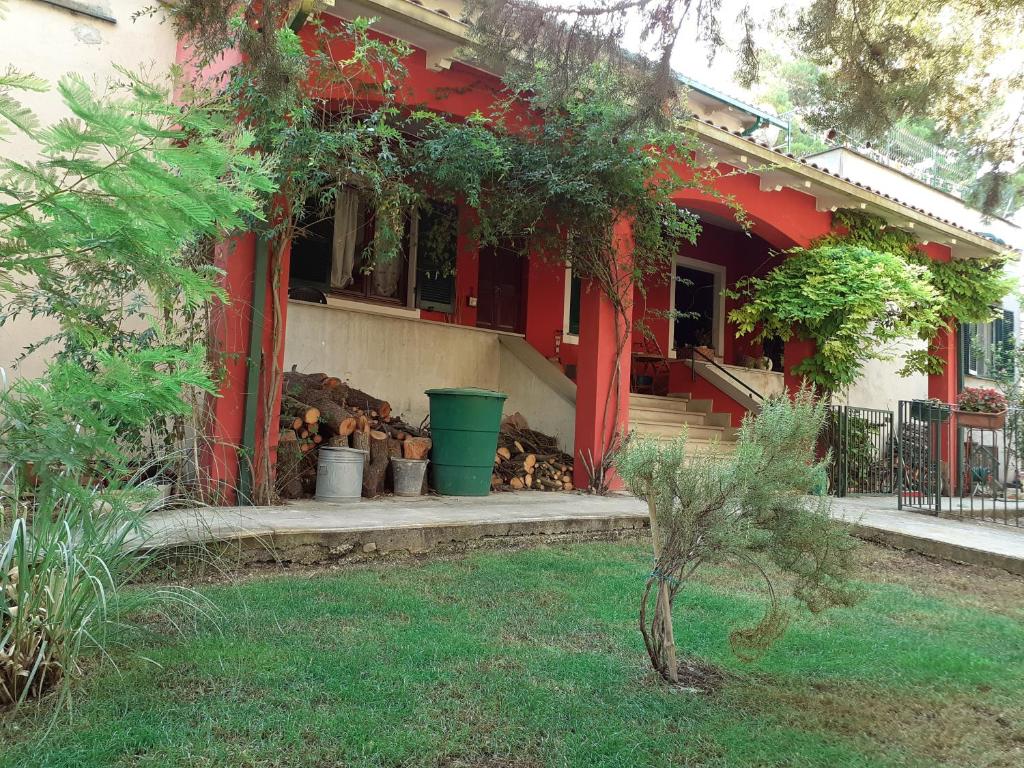 une maison rouge avec une terrasse couverte à l'avant ornée de plantes dans l'établissement Villa con Piscina in Umbria, à Foligno