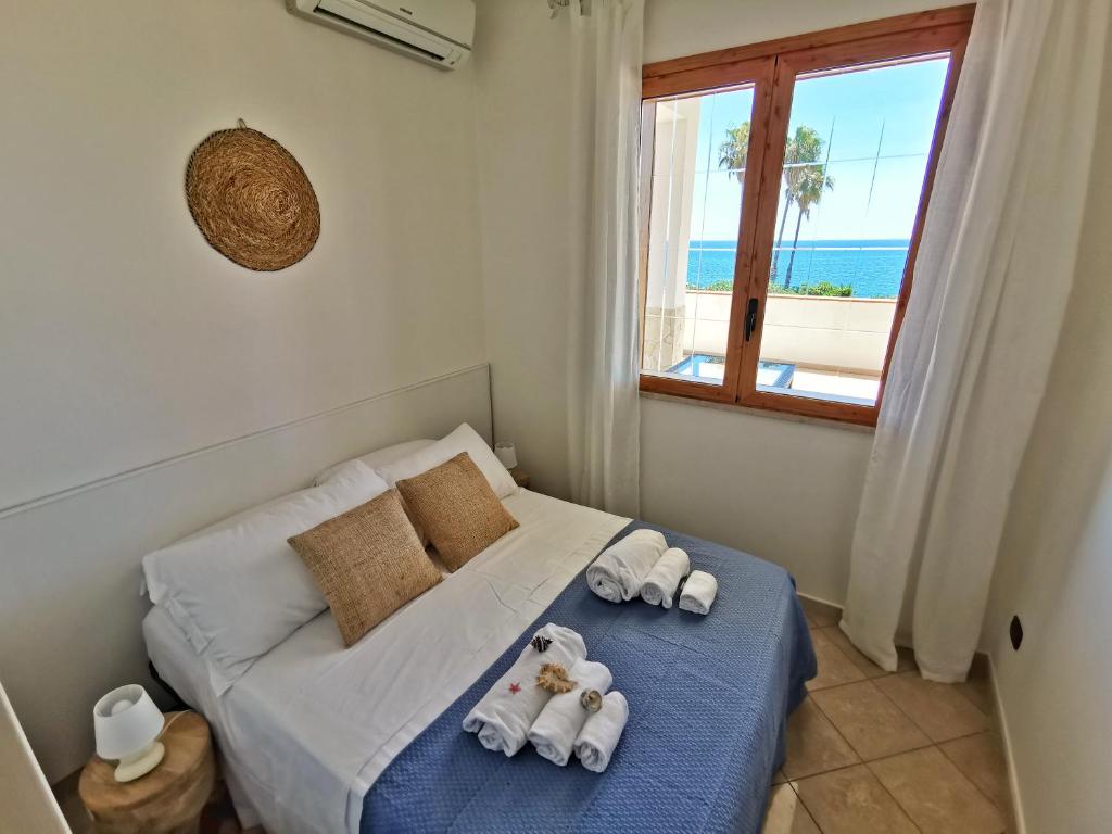 - une chambre avec un lit, des serviettes et une fenêtre dans l'établissement Villa Arenile - Seaside - Swimmingpool- Private access to Sea - waterfront - Fontane Bianche - Siracusa, à Fontane Bianche