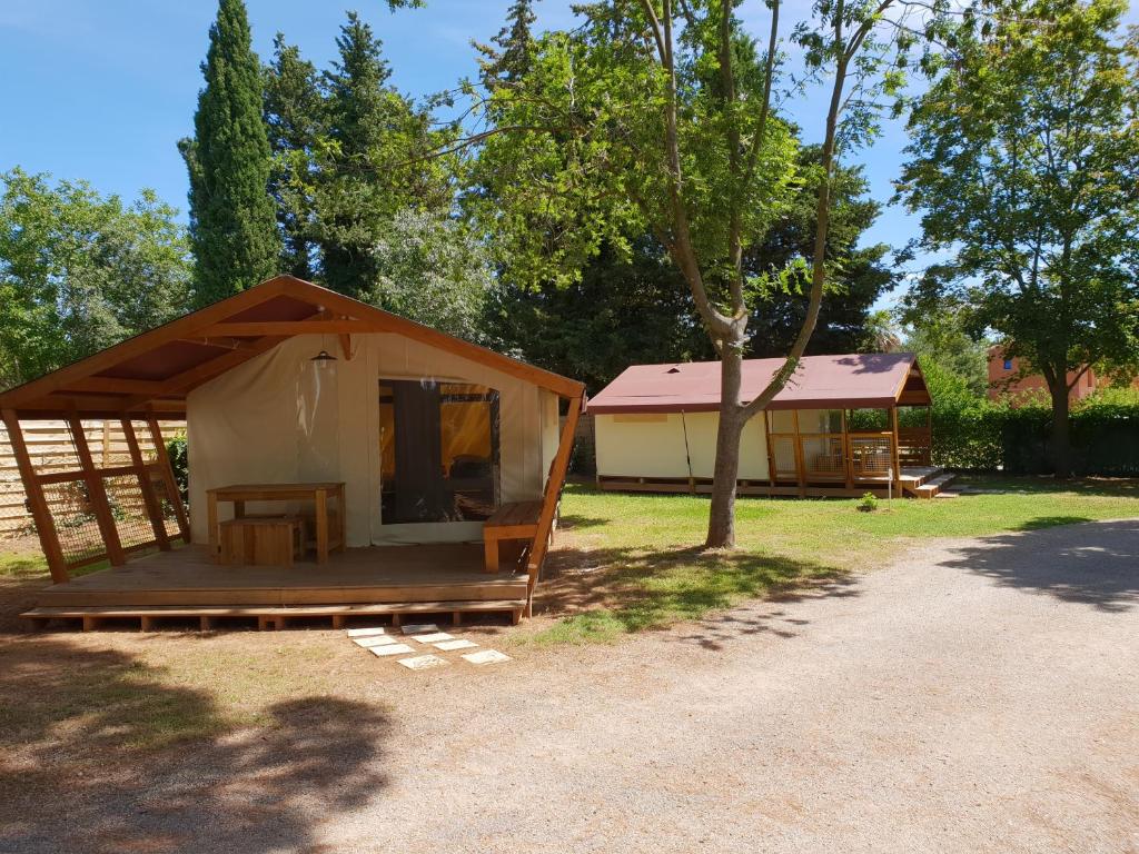 une grande tente avec une table et un arbre dans l'établissement Camping Le Fou du Roi, à Lansargues