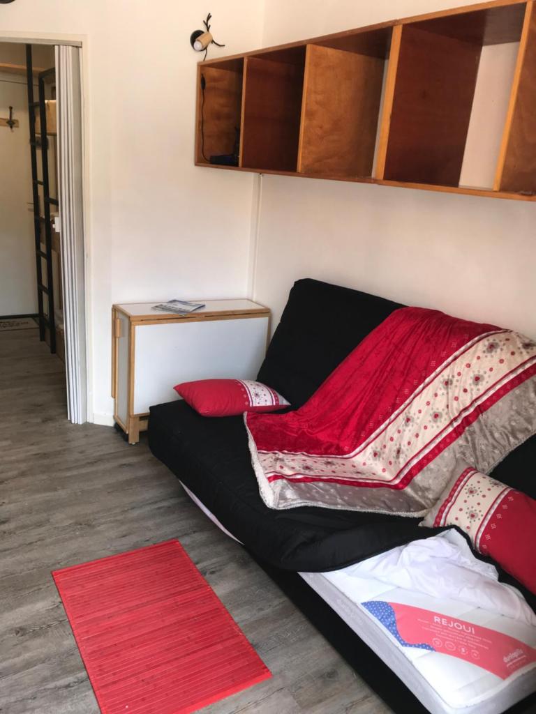 un salon avec un canapé noir avec des coussins rouges dans l'établissement Studio chaleureux à la Foux D’Allos, à Allos