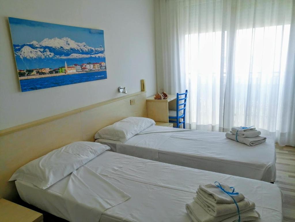 une chambre d'hôtel avec deux lits et une fenêtre dans l'établissement Hotel Souvenir, à Caorle