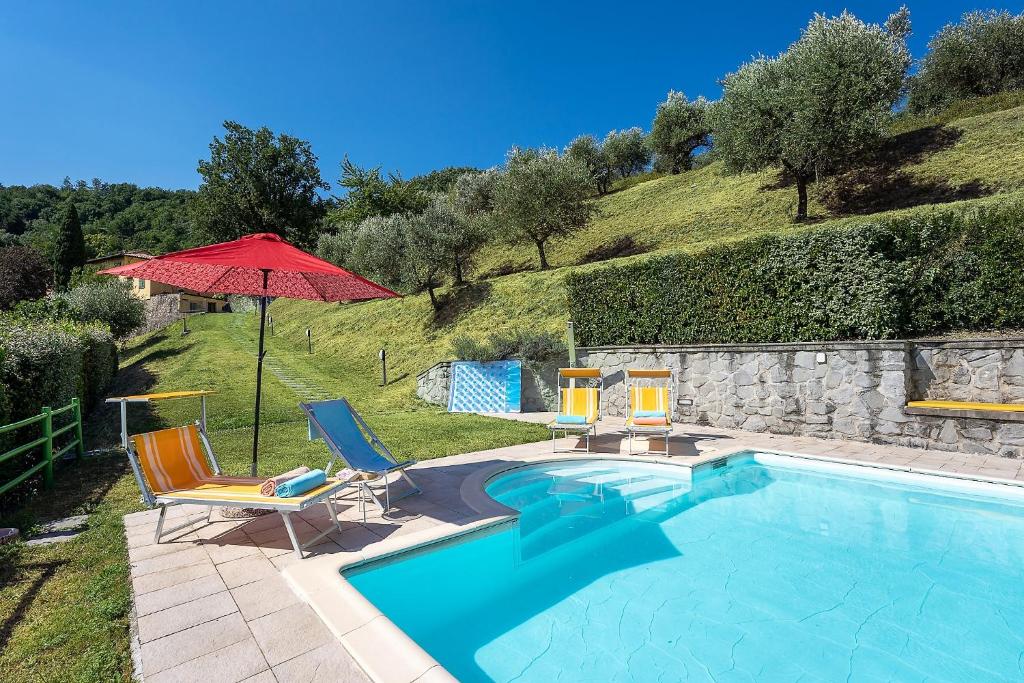 une piscine avec des chaises et un parasol dans l'établissement Villa Mario, piscina privata,aria cond,immersa nel verde,campagna Toscana, à Pistoia