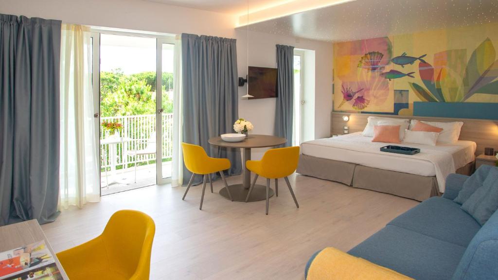 une chambre d'hôtel avec un lit, une table et des chaises dans l'établissement Hotel President, à Lignano Sabbiadoro 53 autres photos
