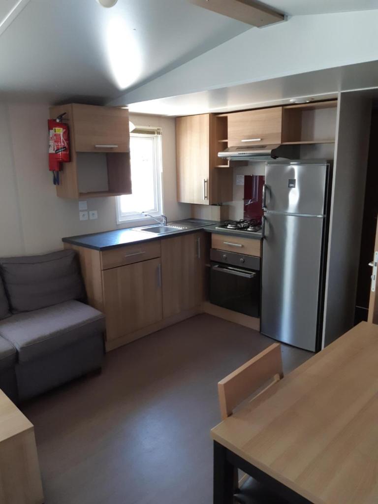 Il comprend une cuisine équipée d'un réfrigérateur en acier inoxydable et d'un canapé. dans l'établissement Mobil-home Confort camping le bois Masson, à Saint-Jean-de-Monts
