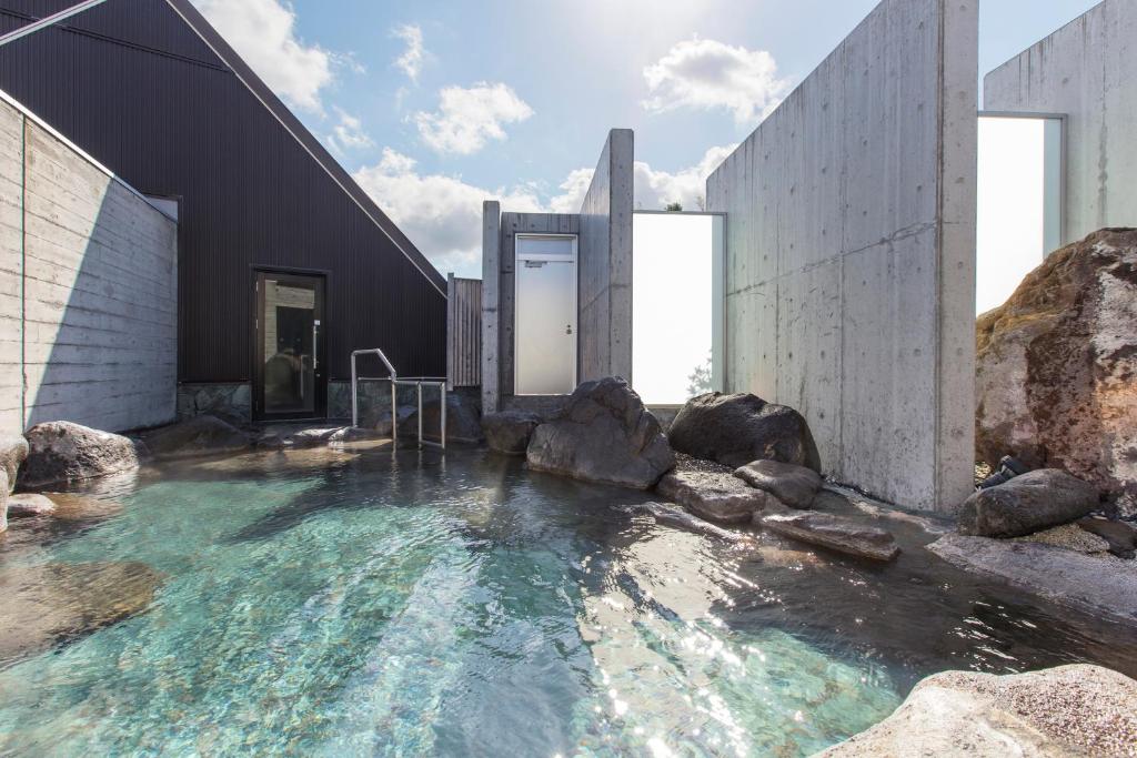 - un bâtiment avec piscine d'eau et rochers dans l'établissement Horohoro Sanso, à Date