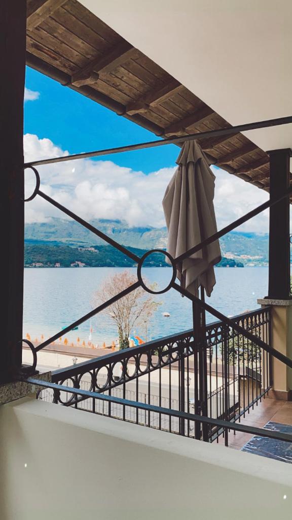 une vue sur la plage depuis un balcon avec un parasol dans l'établissement Hotel Fontaine Bleue, à Orta San Giulio