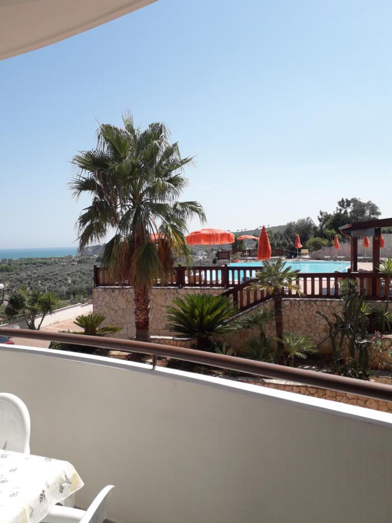 - un balcon avec un palmier offrant une vue sur l'océan dans l'établissement Villa dei pini, à Vieste