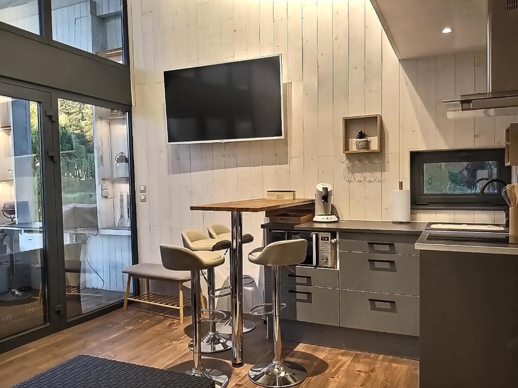une cuisine avec un bar avec des tabourets et une télévision murale dans l'établissement Les Kabanes de Kerforn, à Crach