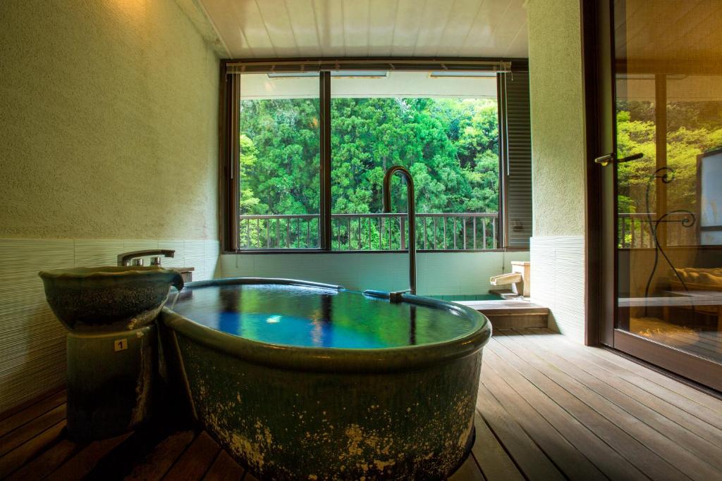 une salle de bain avec une grande baignoire et une fenêtre dans l'établissement Yamanakaonsen Ohanami Kyubei, à Kaga