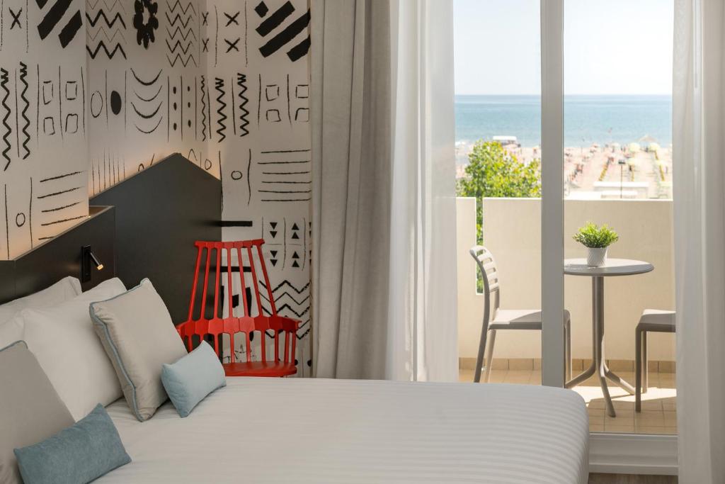 une chambre avec un lit et une vue sur la plage dans l'établissement Litoraneo Suite Hotel, à Rimini