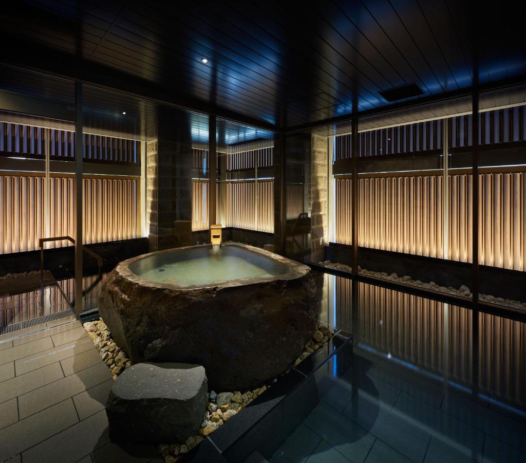 - une grande baignoire dans une chambre avec un grand rocher dans l'établissement ONSEN RYOKAN Yuen Sapporo, à Sapporo