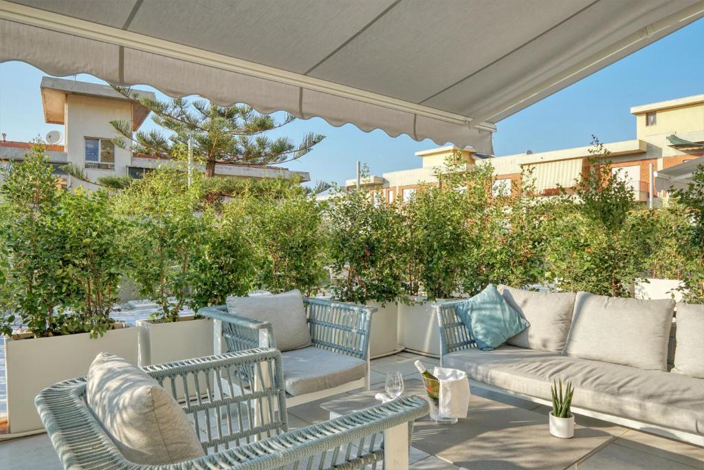 une terrasse avec un canapé, des chaises et des arbres dans l'établissement Horizon Suites, à Cefalù