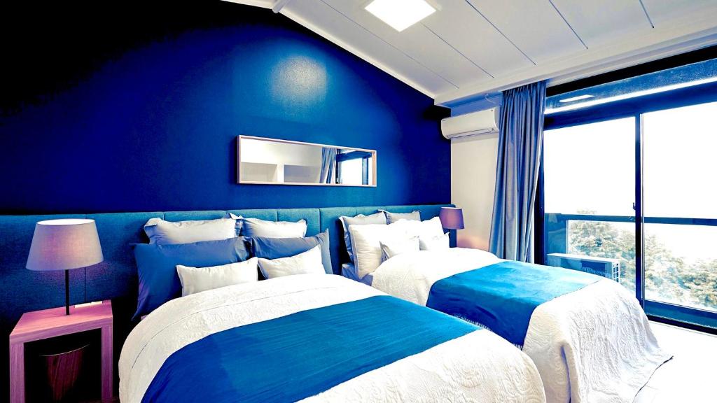 deux lits dans une chambre aux murs bleus dans l'établissement gran terrace Le Lien Hakone, à Hakone