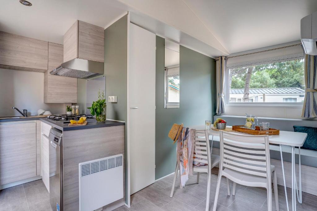une cuisine avec une table et des chaises dans une pièce dans l'établissement Camping Le Bois Fleuri, à Argelès-sur-Mer 37 autres photos