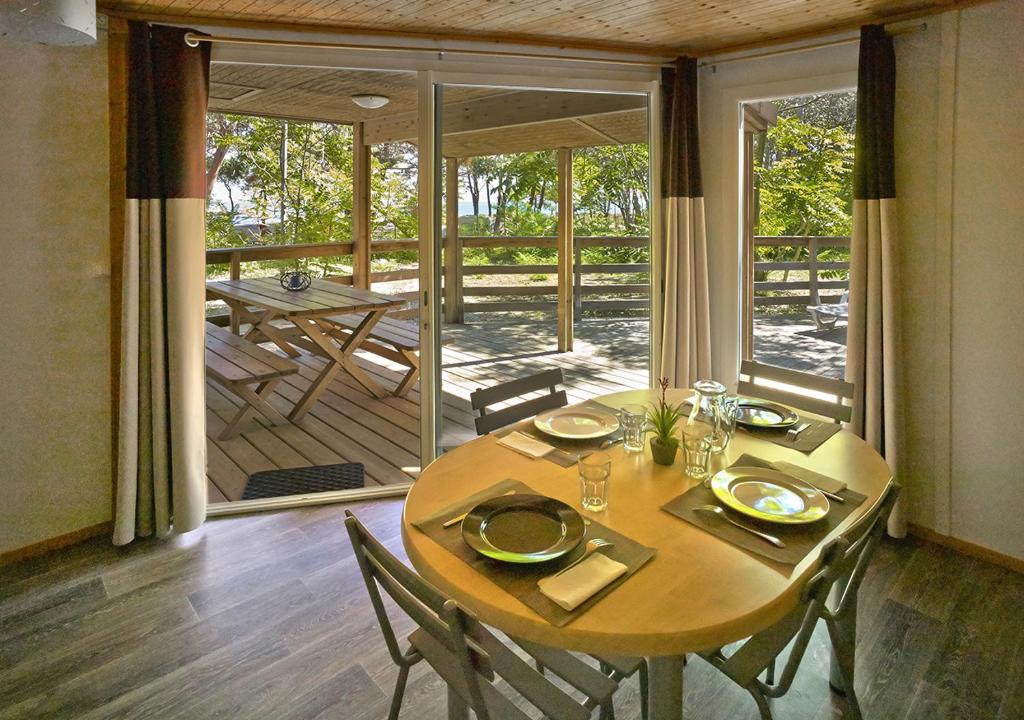une salle à manger avec une table et des chaises ainsi qu'une terrasse dans l'établissement Camping San Damiano, à Biguglia