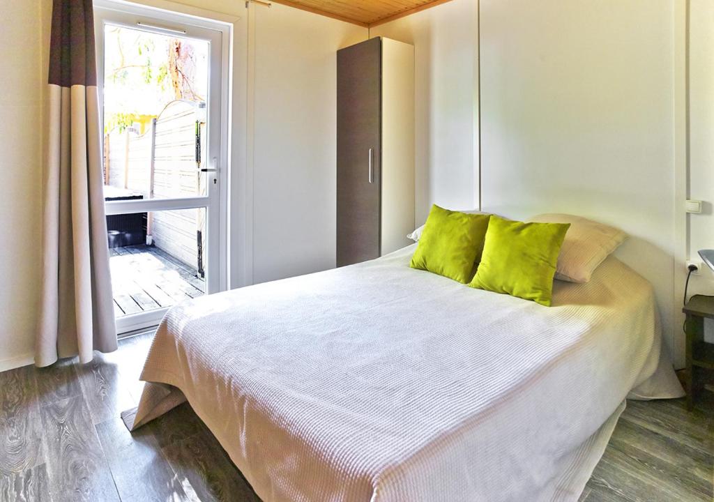 une chambre avec un lit avec des oreillers verts et une fenêtre dans l'établissement Camping San Damiano, à Biguglia 37 autres photos
