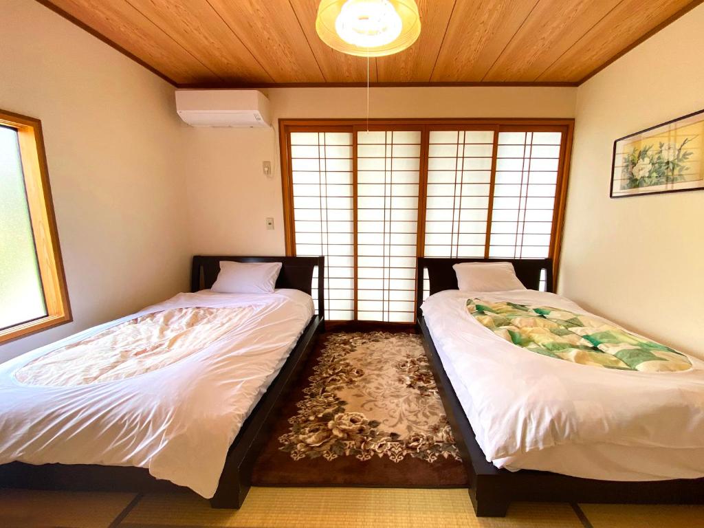 deux lits dans une chambre avec deux fenêtres dans l'établissement Yufuin Onsen Hasuwa Inn, à Yufu 82 autres photos