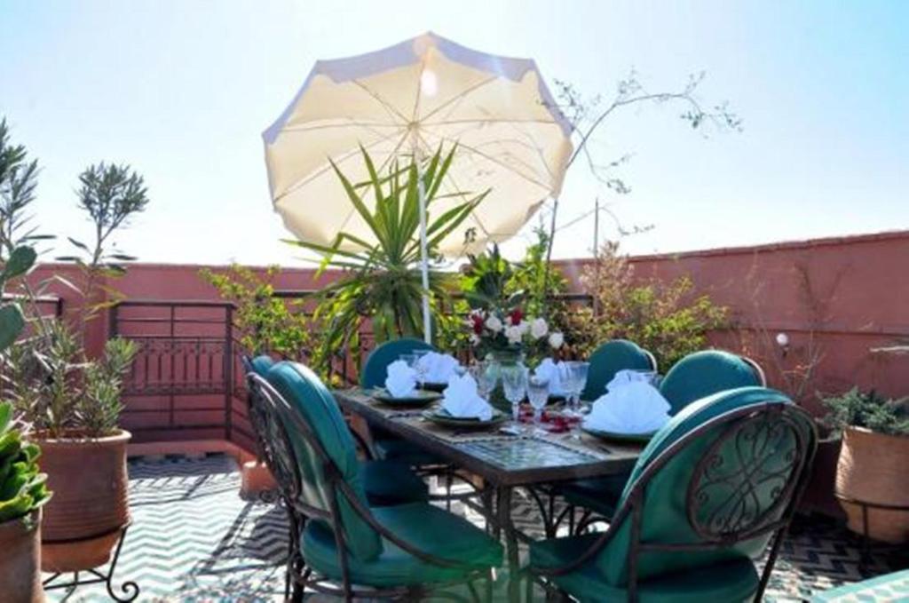 un patio avec une table, des chaises et un parasol dans l'établissement Riad La Perle de Marrakech, à Marrakech