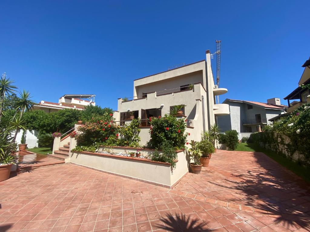 une maison blanche avec des plantes en pot dans une allée en briques dans l'établissement ALBA SULLO STRETTO, à Messina