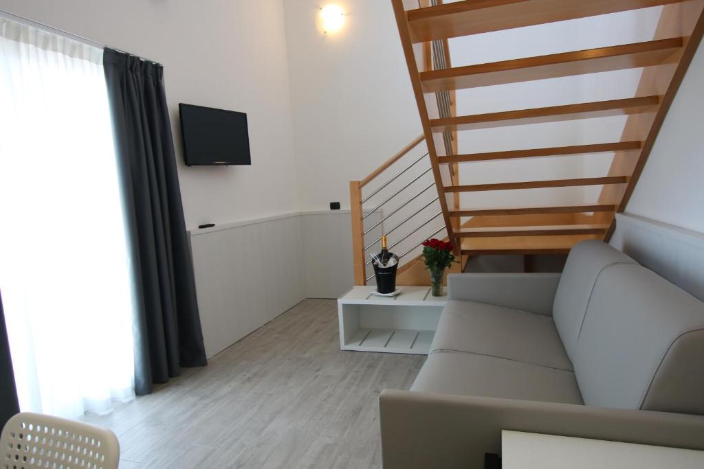 un salon avec un canapé et un escalier dans l'établissement Eraclea Palace Hotel 4 stelle S, à Eraclea Mare