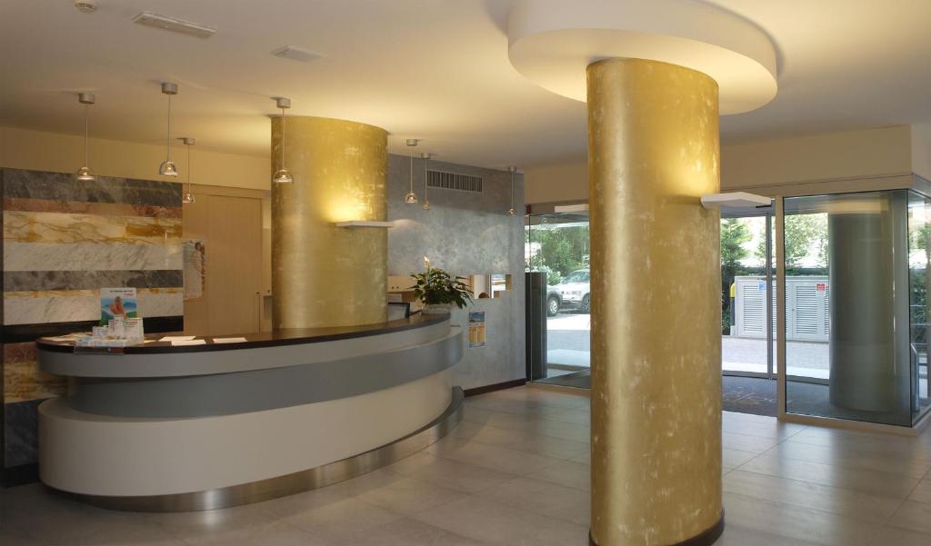 un hall avec deux colonnes d'or et un comptoir dans l'établissement Eraclea Palace Appartements, à Eraclea Mare