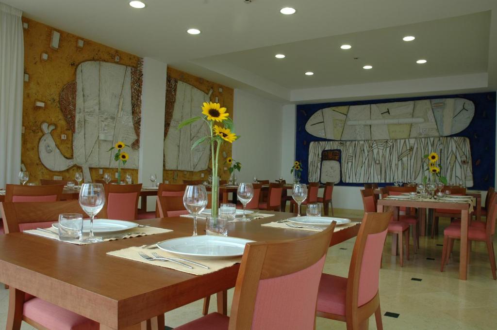 une salle à manger avec une table, des verres et un vase avec un tournesol dans l'établissement Casa Rossa 1888, à Torre del Greco