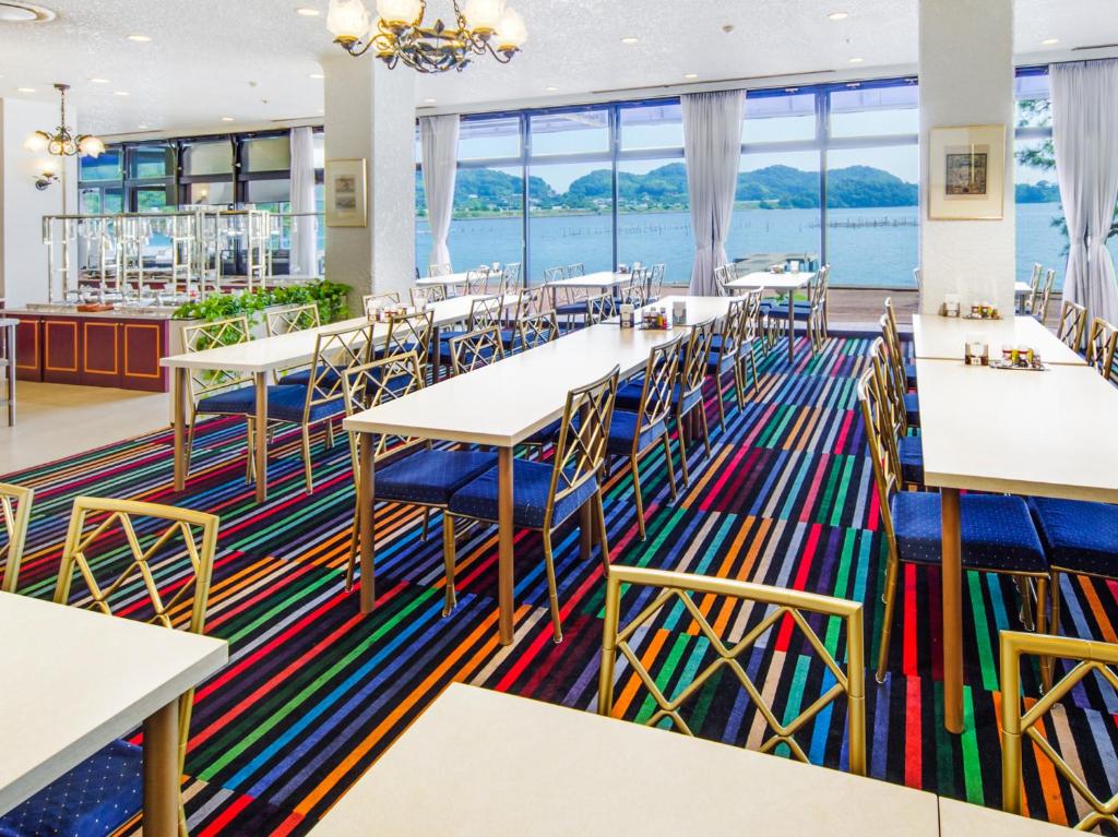 une salle à manger avec tables et chaises et une grande fenêtre dans l'établissement Hotel Green Plaza Hamanako, à Hamamatsu 35 autres photos