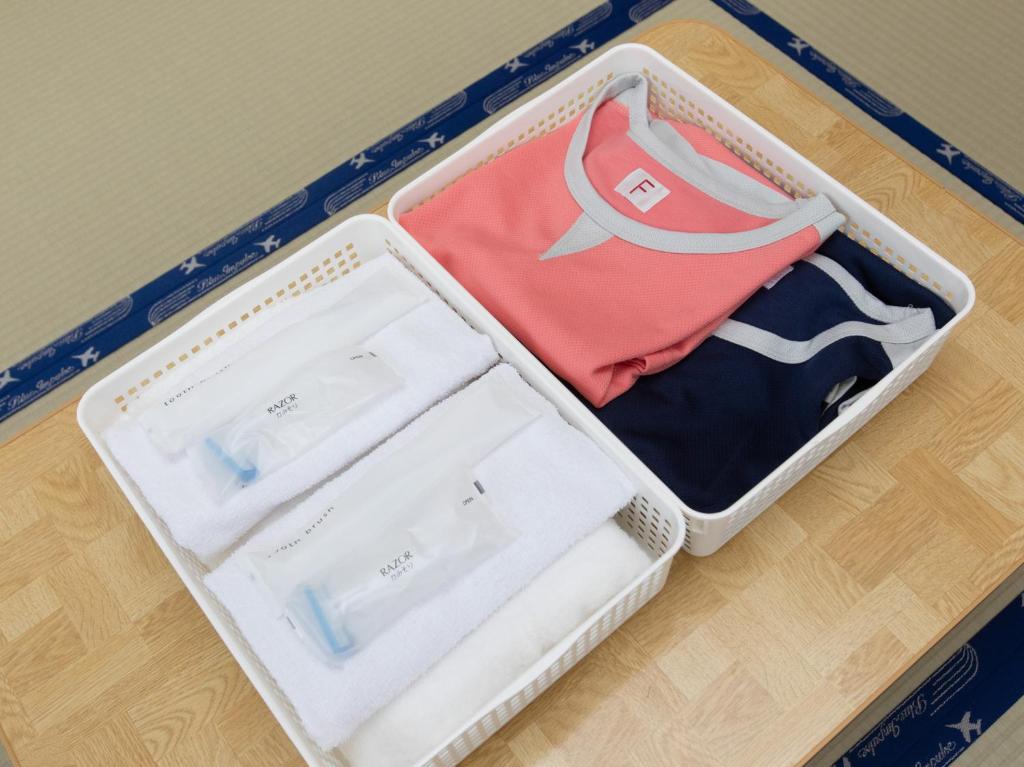 une valise remplie de vêtements sur du parquet dans l'établissement Tabist Business Ryokan Duck Ishinomaki Hebita, à Ishinomaki