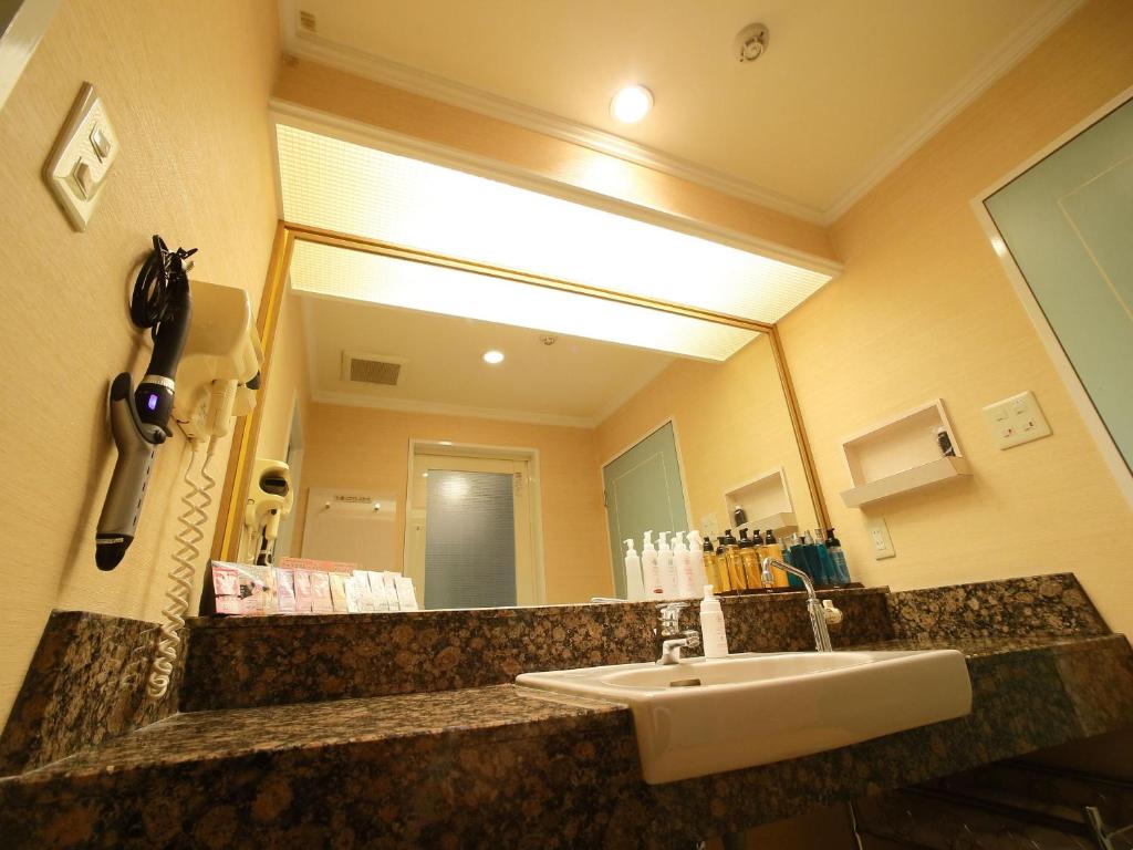 une salle de bain avec un lavabo et un grand miroir dans l'établissement Hotel Fine Garden Senboku, à Sakai 18 autres photos